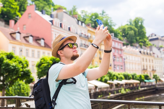 Rückansicht eines jungen Mannes, der in der Stadt ein Foto mit dem Smartphone macht