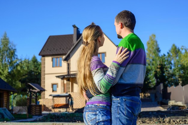 Rückansicht eines jungen Paares, das sein neues Haus betrachtet