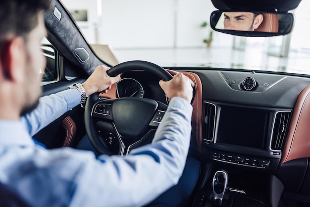 Rückansicht eines kaukasischen seriösen Geschäftsmannes, der ein Auto fährt