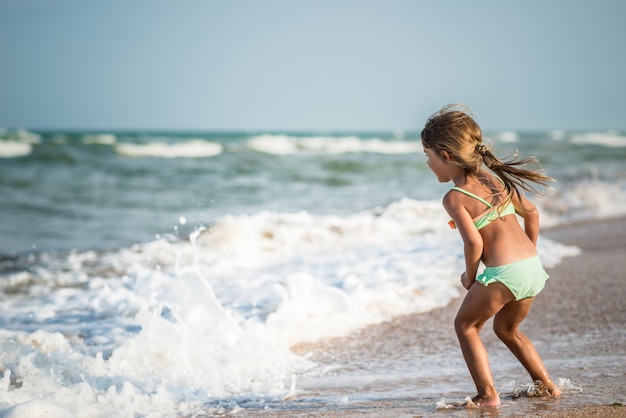 Rückansicht eines kleinen vierjährigen Mädchens, das an einem warmen Sommertag während der Sommerferien in einem tropischen Land im Meer schwimmt