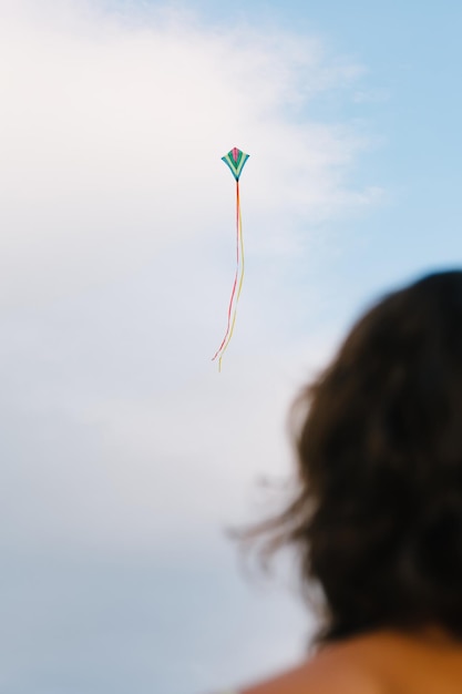 Foto rückansicht eines mädchens, das steht und den drachen betrachtet, der hoch am himmel fliegt