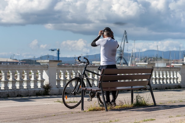 Rückansicht eines Mannes, der seinen Helm aufsetzt, bevor er entlang der Stadtpromenade fährt