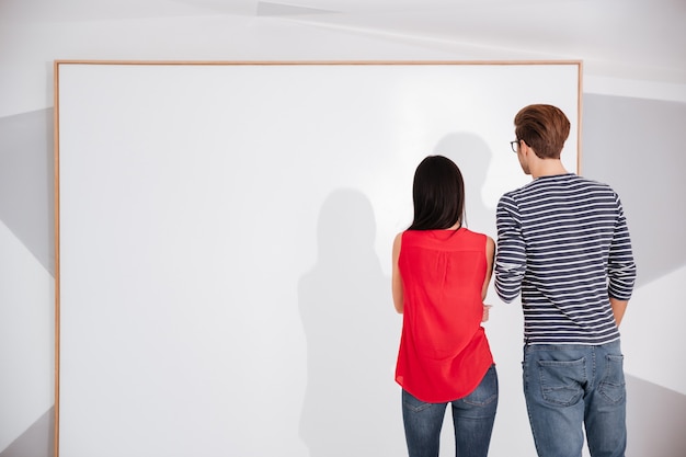 Rückansicht eines Paares auf Ausstellung mit Blick auf leere leere Tafel