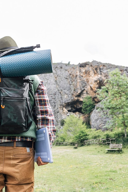 Rückansicht eines Rucksacktouristen mit Hut und Matte in der Natur, unabhängiger Lebensstil, Platz für Text