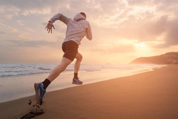 Rückansicht eines Sportlers, der schnell am Strand läuft