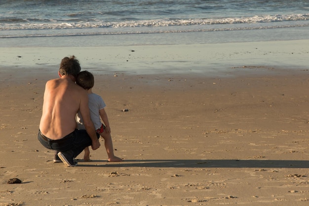 Rückansicht eines Vaters mit seinem Sohn am Strand Zukunftskonzept