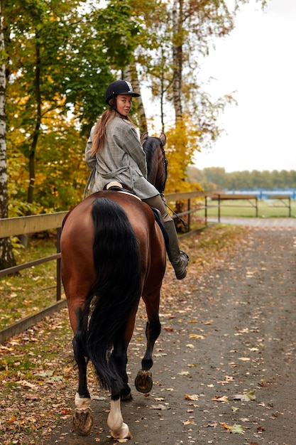 Rückansicht erschossen Porträt einer hübschen jungen Frau mit einem braunen Reiten Herbsttag