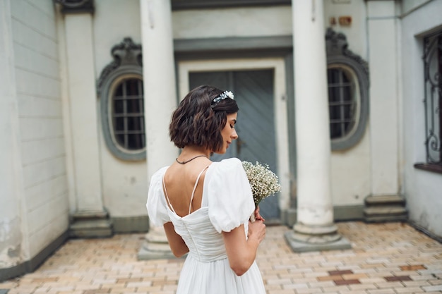 Rückansicht Holding Blumen Braut im Kleid ist im Freien, bevor ihre Hochzeit beginnt