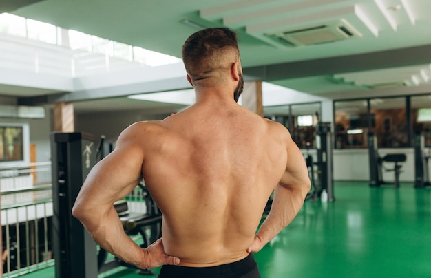 Rückansicht muskulöser Mann mit Rückenmuskulatur im Fitnessstudio Starkes männliches Training mit nacktem Oberkörper