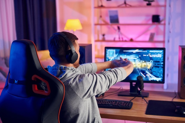 Foto rückansicht online-streamer, der zu hause ein fps-shooter-spiel spielt