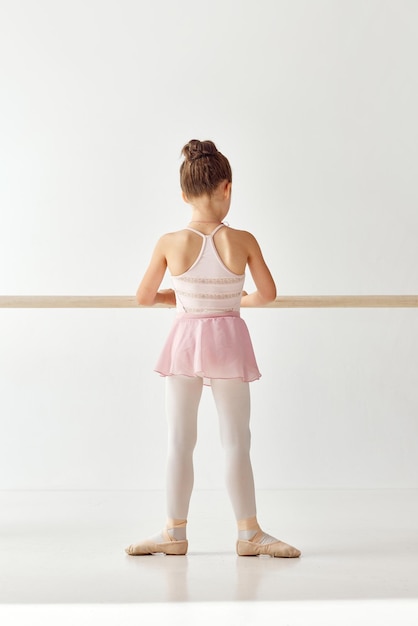 Foto rückansicht-porträt einer kleinen entzückenden ballerina-tänzerin im rosafarbenen tutu-ballettkleid mit weißen leggings