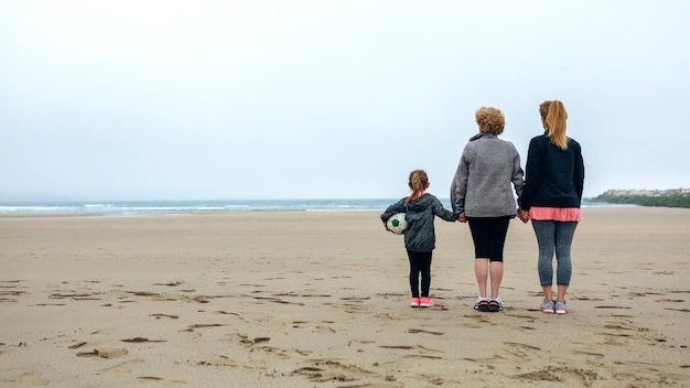 Rückansicht von Frauen aus drei Generationen, die im Herbst das Meer beobachten
