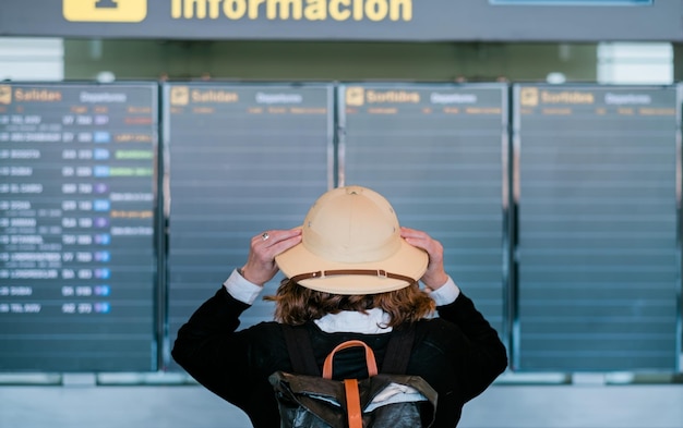 Rückansicht von touristisch aussehenden Flügen in Abflugbildschirmen am Flughafen