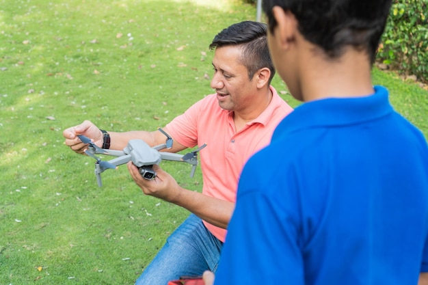 Rückansicht von Vater und Sohn, die im Sommer eine Drohne über das Feld fliegen