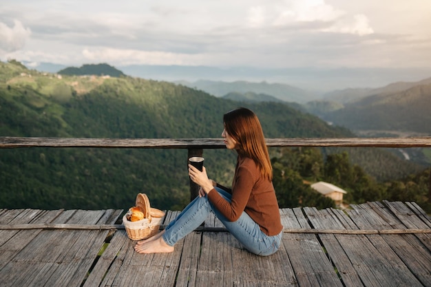 Rückansichtbild einer Reisenden, die sitzt und ein wunderschönes Bergblumenfeld und eine Naturansicht betrachtetxAxA