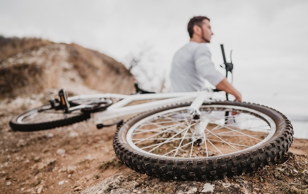 Foto rückansichtmann, der neben seinem mountainbike sitzt