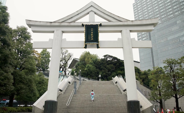 Foto rücken schrein und stufen mit japanischer frau, die in der stadt tempel für glauben glauben oder religion gebäude anbetung und standort mit person auf der treppe in tokio für tradition achtsamkeit oder abenteuer