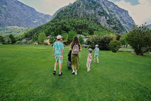 Rückseite der Mutter mit Kinderwagen und Kindern zu Fuß gegen die österreichischen Alpen in Hallstatt Salzkammergut Österreich