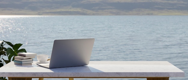 Rückseite des Laptopmodells auf weißem Marmortisch mit Kopienraumseelandschaft im Hintergrund