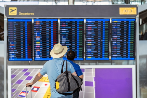 Rückseite des Reisenden mit dem Gepäck, das über dem Flugbrett für Abfertigung steht