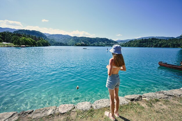 Rückseite des Teenager-Mädchens in Panama steht im Pier mit Blick auf den schönen Bleder See Slowenien