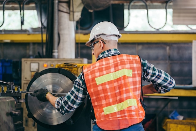 Rückseite des Vorarbeiters oder Fabrikarbeiters, der mit der Drehmaschine arbeitet