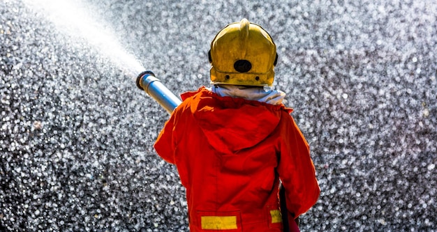 Foto rückseite eines feuerwehrmanns, der wasser besprüht