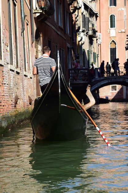 Rückseite eines Mannes auf einer Gondel, der im Kanal segelt