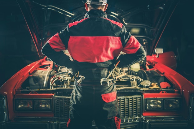 Foto rückseite eines mechanikers, der in der werkstatt neben einem auto steht