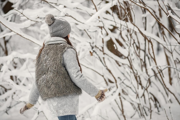 Rückseitenfoto eines brünetten Mädchens mit Strickmütze und grauer Jacke im Winter