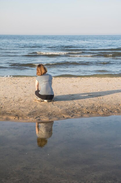 Foto rückwand einer frau, die am strand sitzt