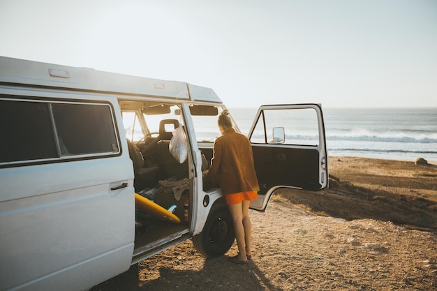 Rückwand einer Frau, die vor einem Campingwagen am Strand vor klarem Himmel steht