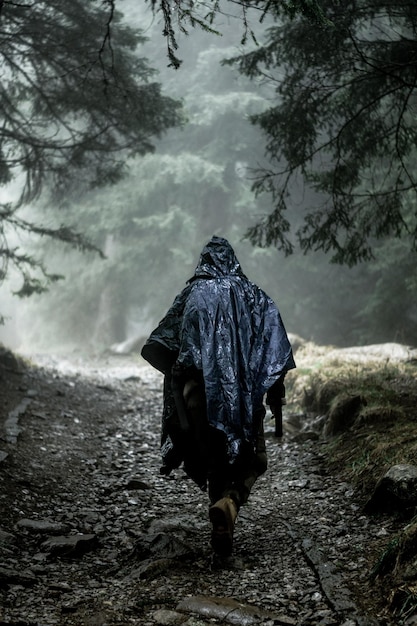 Rückwand einer Person, die während der Regenzeit auf einem nassen Fußweg geht