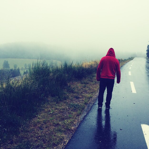 Foto rückwand eines mannes, der bei nebligem wetter auf einer nassen straße geht