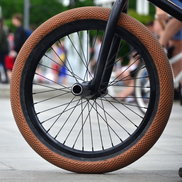 Una rueda de bicicleta BMX en el contexto de una calle borrosa con ciclistas