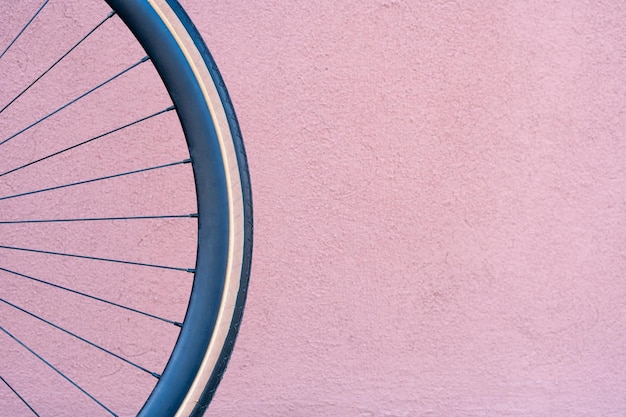 Rueda de bicicleta en el fondo de una pared naranja Bicicleta fija de moda Llanta negra y neumático beige Objeto redondo para publicidad