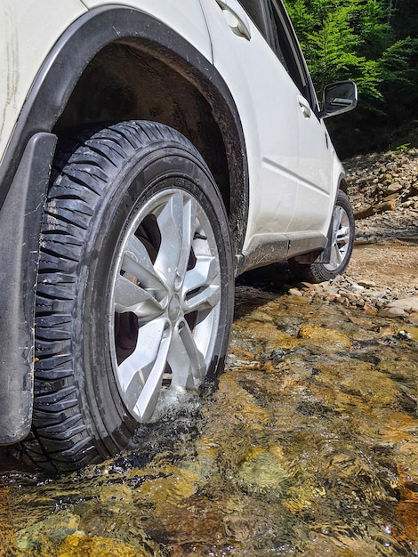 Rueda de cierre de coche todoterreno en agua de arroyo de montaña