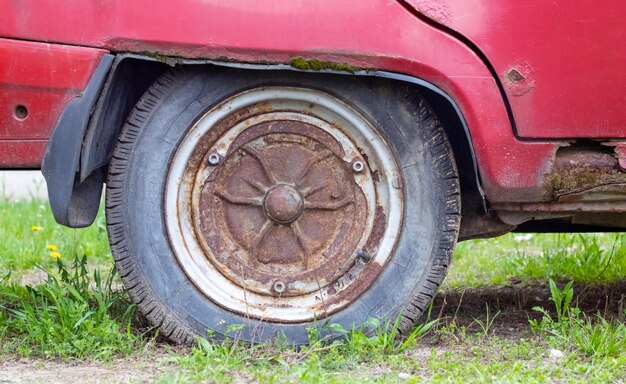 Rueda de coche desgastada con suciedad y mugre Coche abandonado oxidado en el estacionamiento Restauración