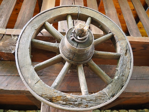 Foto una rueda es un motor, un disco que gira libremente o está fijado sobre un eje giratorio, lo que permite que el cuerpo colocado sobre él ruede en lugar de deslizarse. rueda de madera de un carro o carreta, pueblo étnico de stanisici.