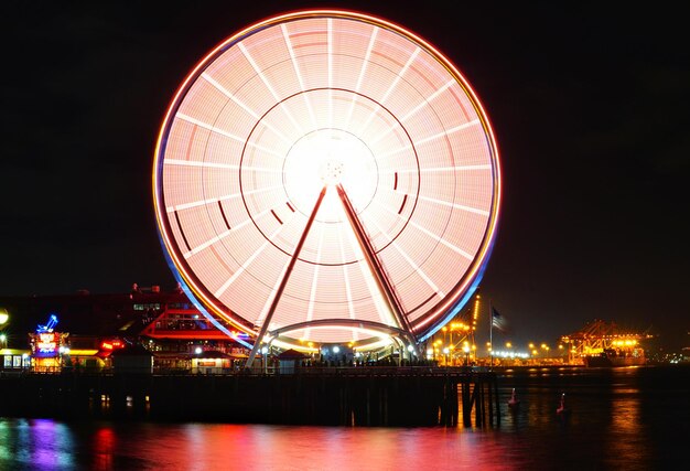 Foto rueda gigante iluminada por el río contra el cielo por la noche