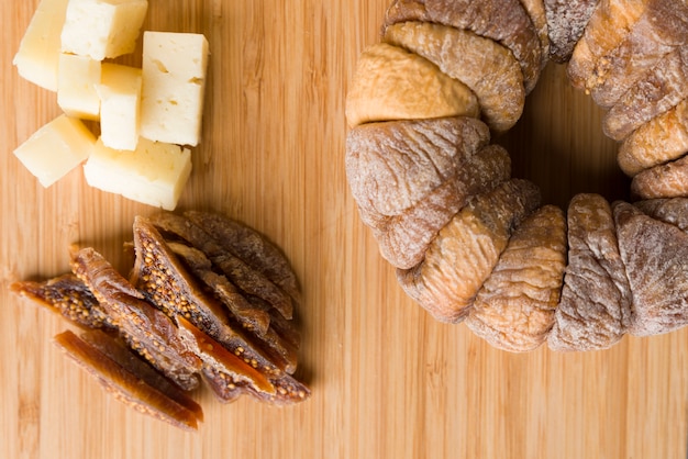 Rueda de higos secos con un higo seco cortado en rodajas junto a trozos de pecorino sobre una tabla de madera