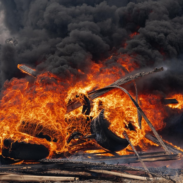 Ruedas de automóvil en llamas llama fuerte de fuego rojo y nubes negras en el cielo