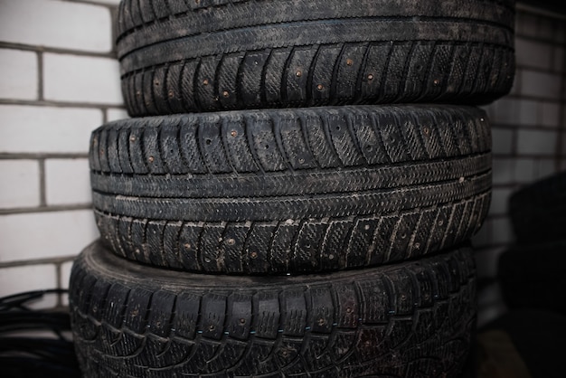 Ruedas de automóvil usadas plegadas horizontalmente. Neumáticos de coche con púas de invierno desechados, banda de rodadura gastada.