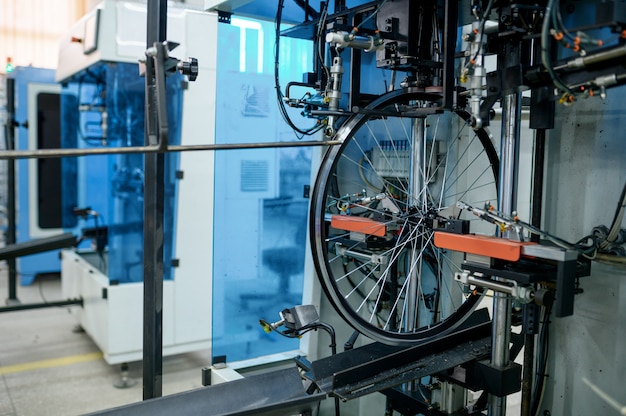 Ruedas de bicicleta de aluminio nuevas en línea de montaje, instalación de radios, nadie. Piezas de bicicleta en fábrica, llantas de ciclo con bujes en la máquina, tecnología moderna