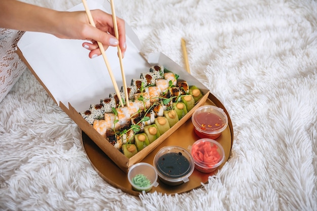 Ruede en la mano de la niña en el contexto de una bandeja con sushi.