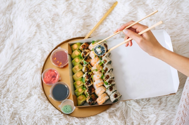 Ruede en la mano de la niña en el contexto de una bandeja con sushi.