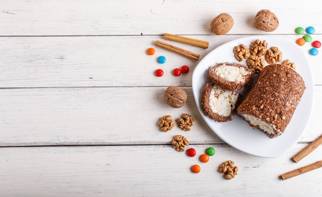 Ruede la torta con la cuajada y las nueces aisladas en el fondo de madera blanco.