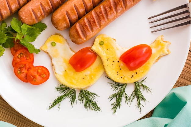 Rührei in Form von Vögeln, Würstchen und Tomaten