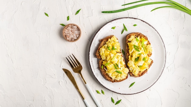 Rührei mit Frühlingszwiebeln auf knusprigem Weizenroggen-Vollkornbrot, hausgemachtem, gesundem Frühstück oder Brunch.