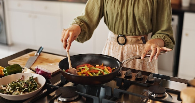 Rühren, Braten und Hände mit Löffel Küche und Mahlzeit Vorbereitung von gesundem Essen Kochen und Frühstück zu Hause Morgen Ernährungswissenschaftler und Person mit Gemüse Prozess und Gastofen für Wärme und Pfanne
